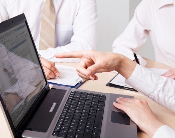 Close-up of a human hand pointing at laptop screen